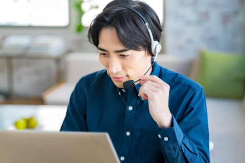 ヘッドセットを着けてノートパソコンに向かう男性