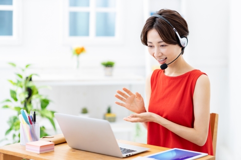 自宅でヘッドセットを着けてパソコンに向かう女性