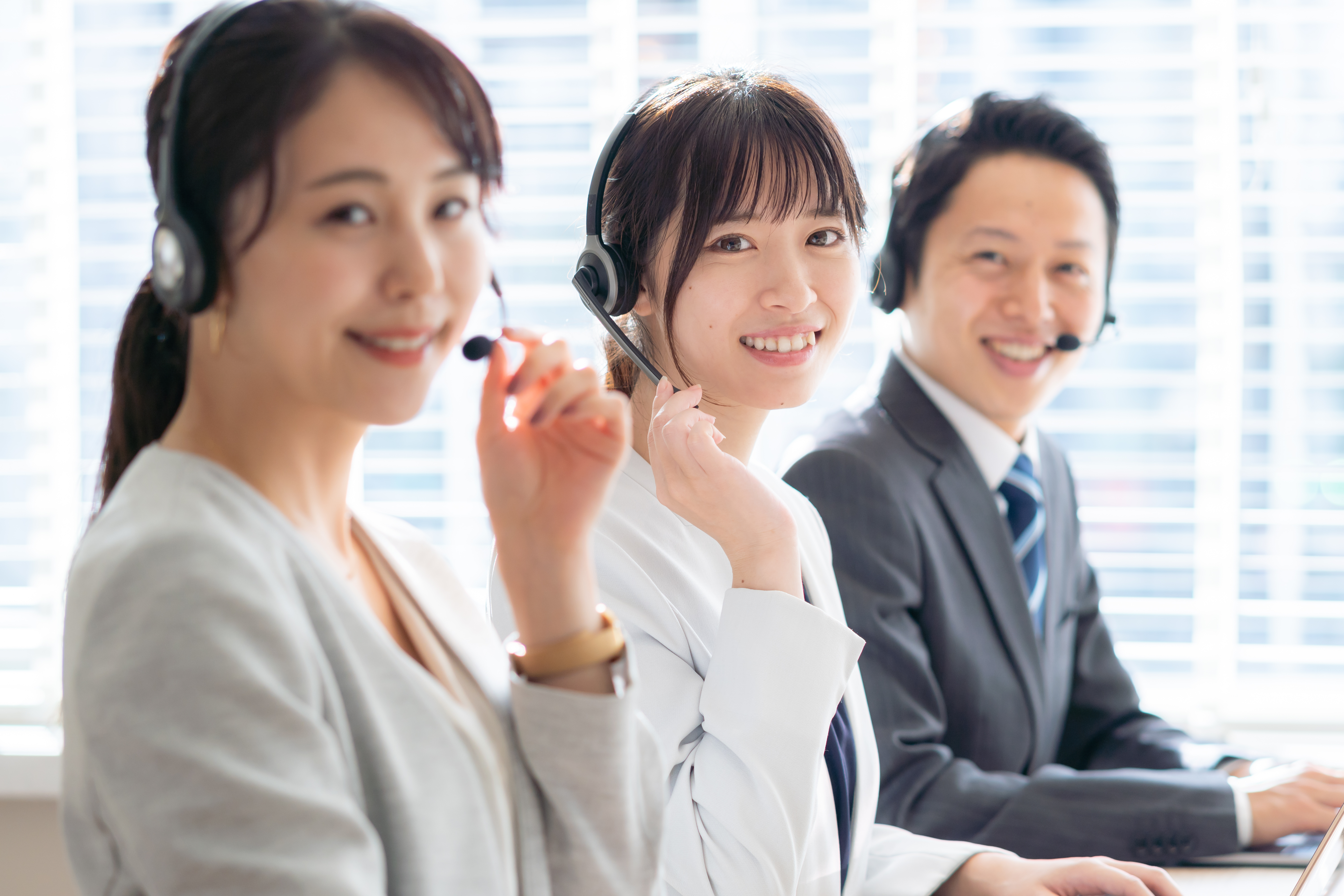 ヘッドセットを着けたスタッフ3名がオフィスで並んで対応する様子